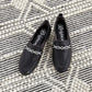 Brighton black leather loafers styled with silver-tone chain hardware and woven detail on a striped woven rug