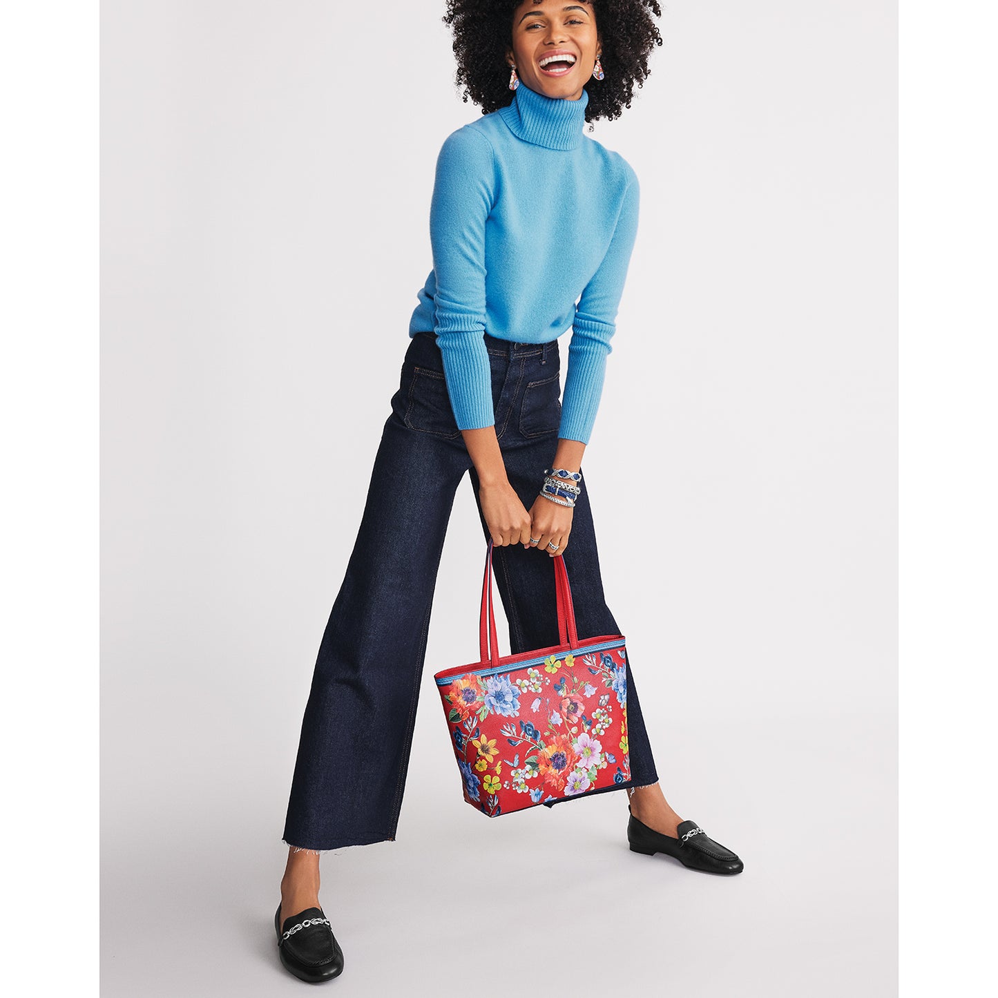 Model with a Brighton red leather tote handbag featuring colorful floral print and dual shoulder straps