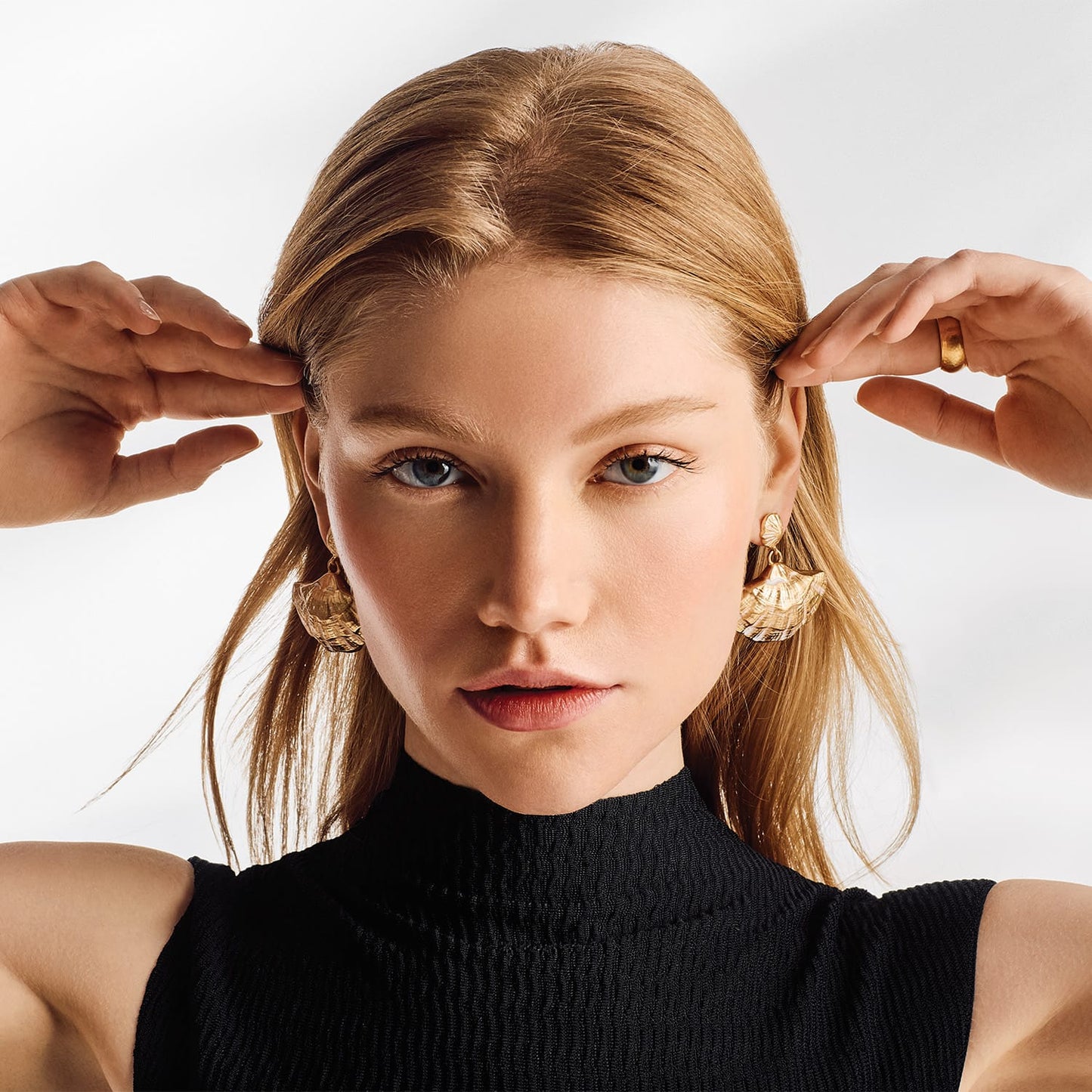 Model wearing Brighton gold-plated drop earrings with layered fan-shaped shell motifs and textured detailing