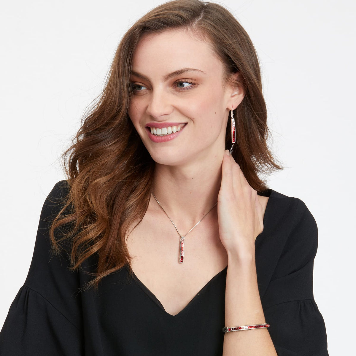 Model wearing a Brighton silver-plated pendant necklace with red crystals paired with matching drop earrings and bracelet