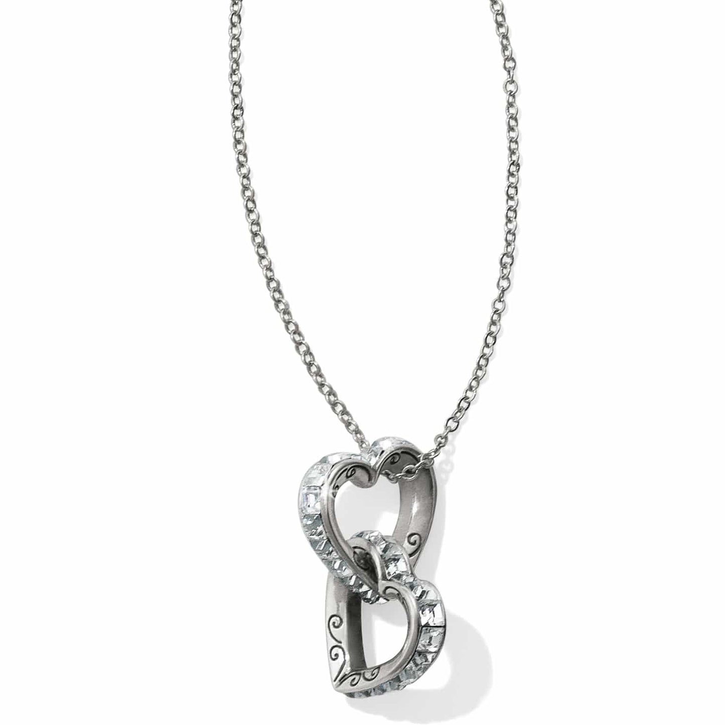 Brighton pendant necklace with two interlocking silver-plated hearts featuring crystal accents and scroll detail on a white background
