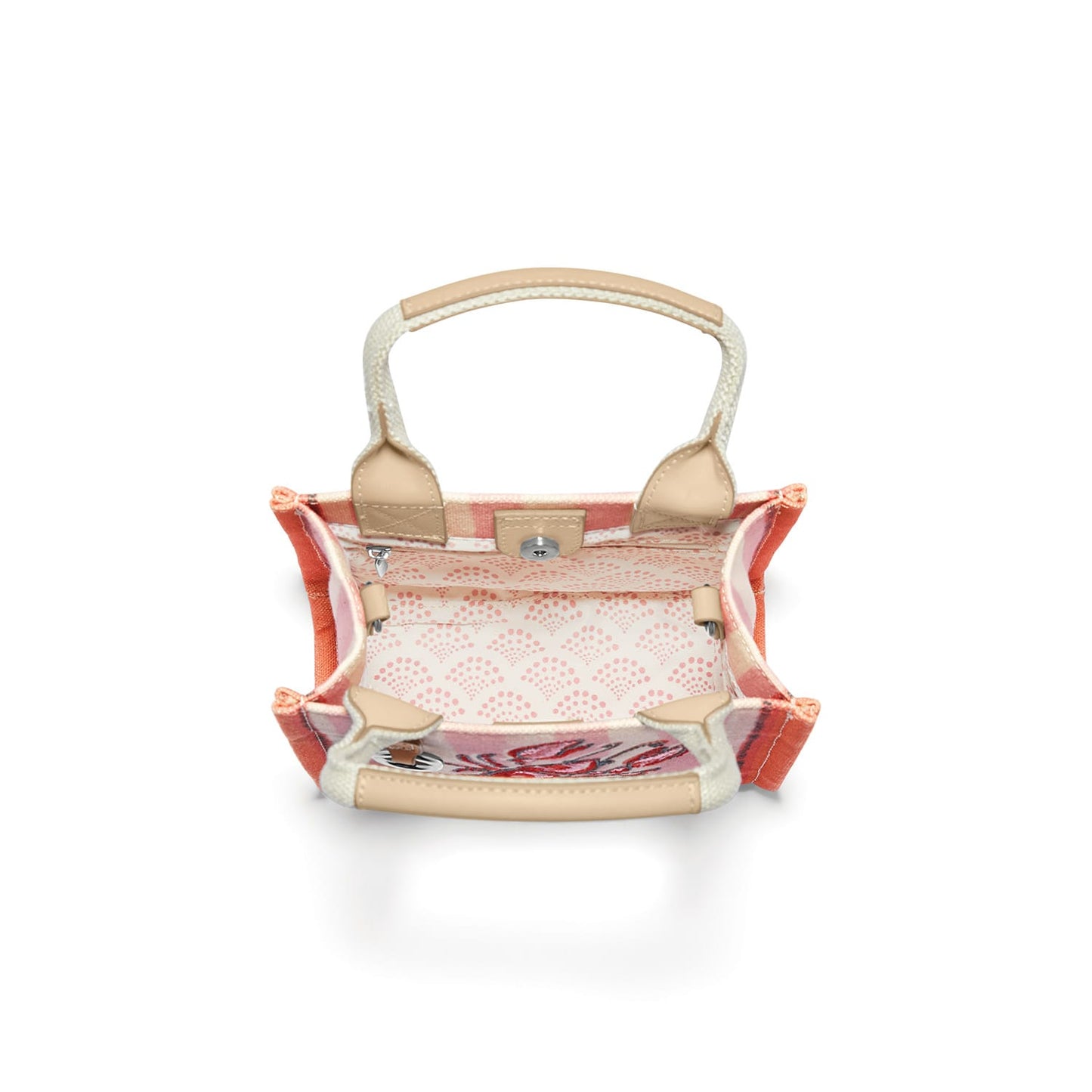 Brighton handbag interior view showing pink patterned lining, tan trim, woven handle, and magnetic closure on a white background