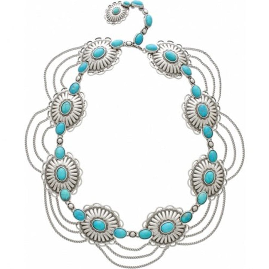 Brighton necklace with dyed turquoise howlite stones, silver-tone concho medallions, and draped chains on a white background