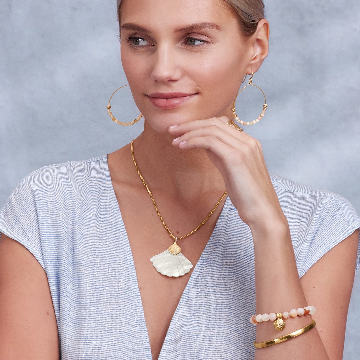 Model wearing a Brighton gold shell pendant necklace with coordinating Brighton beaded hoop earrings and bracelets