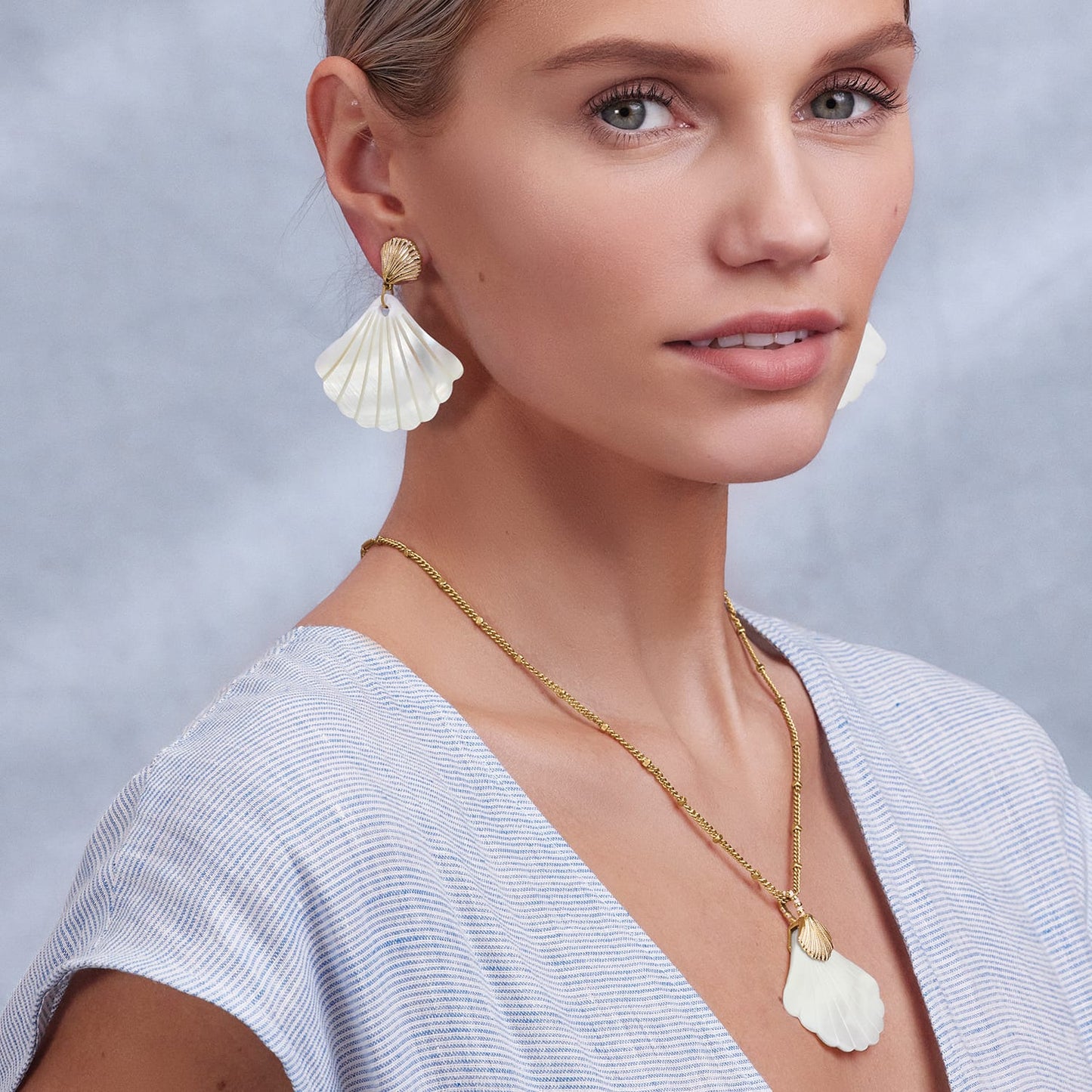 Model wearing Brighton gold-plated shell drop earrings paired with a matching shell pendant necklace on gold chain