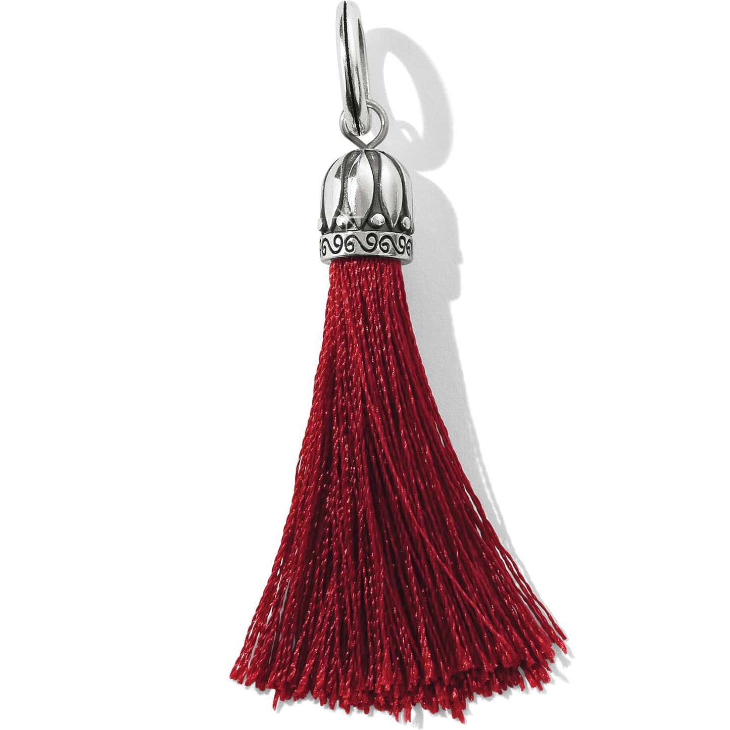 Brighton tassel charm with red fringe and silver-plated ornate cap with scroll detailing on a white background