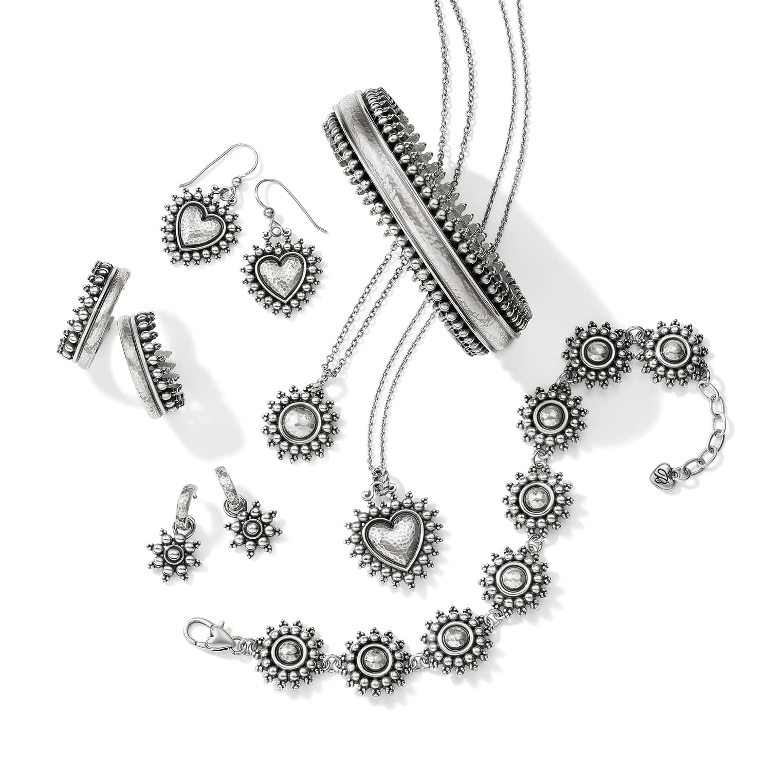 Brighton silver-plated jewelry collection styled with heart earrings, bangle, starburst bracelet, and pendant necklaces on white background