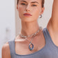 A model wearing the Terra silver Hoop Earrings and a matching necklace with a decorative pendant poses elegantly against a blurred background.