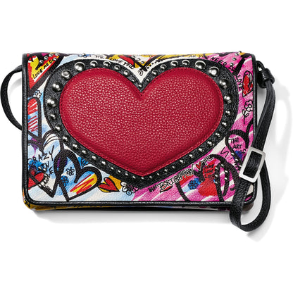 Brighton crossbody handbag with graffiti-style love print, studded red heart center, and black leather strap on a white background