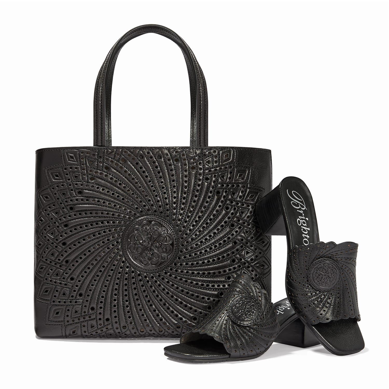 Brighton leather handbag with swirl cutout pattern and medallion, styled with matching heeled sandals on white background