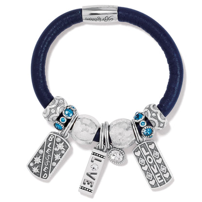 Brighton charm bracelet with navy leather band, silver-plated beads, blue crystals, and Love and Blessed charms on a white background