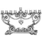 Silver-plated nine-branch menorah with ornate scrollwork, tulip-shaped candle holders, and hanging heart pendant on a white background