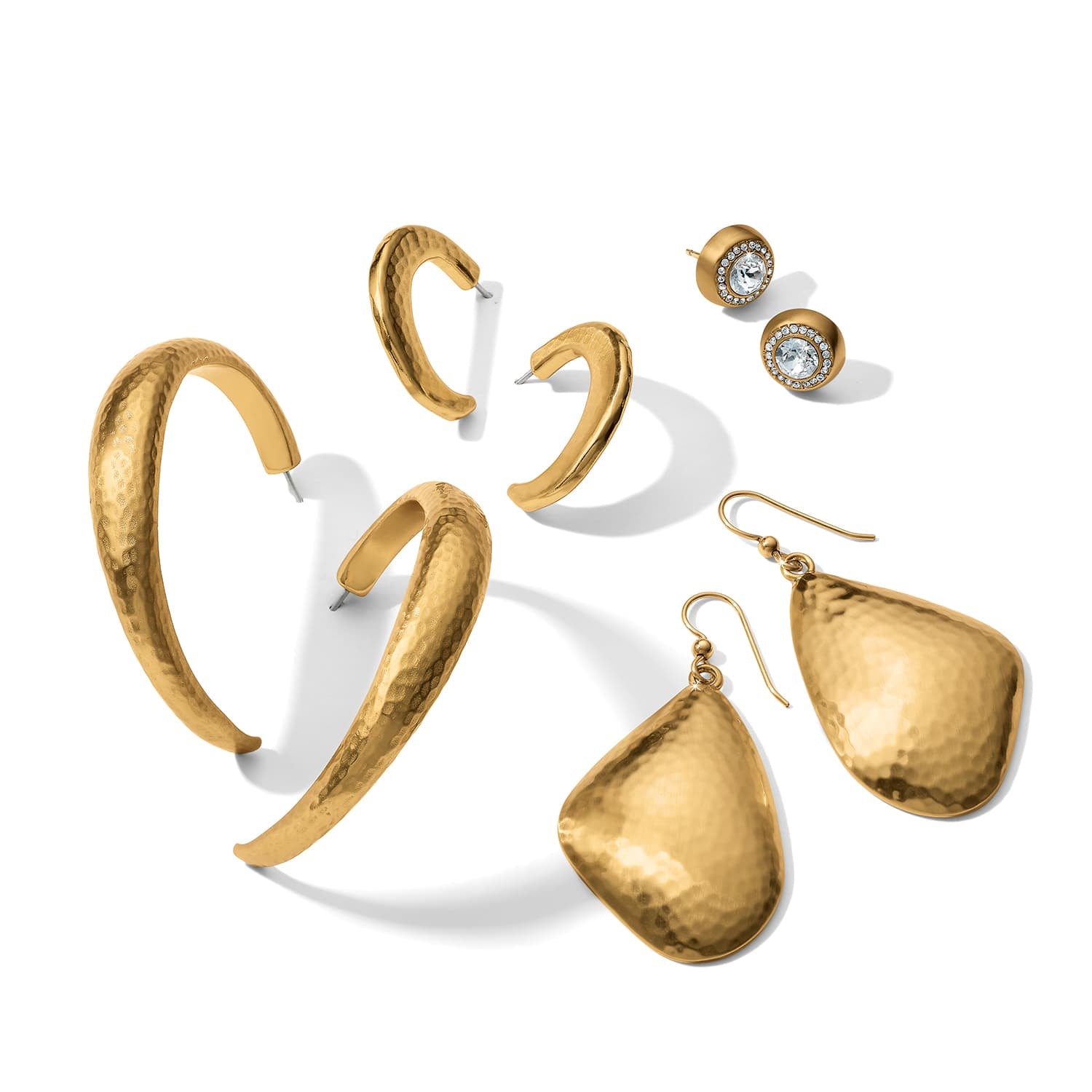 Brighton earrings collection with hammered gold-tone hoops, teardrop drops, and crystal-accented studs on a white background