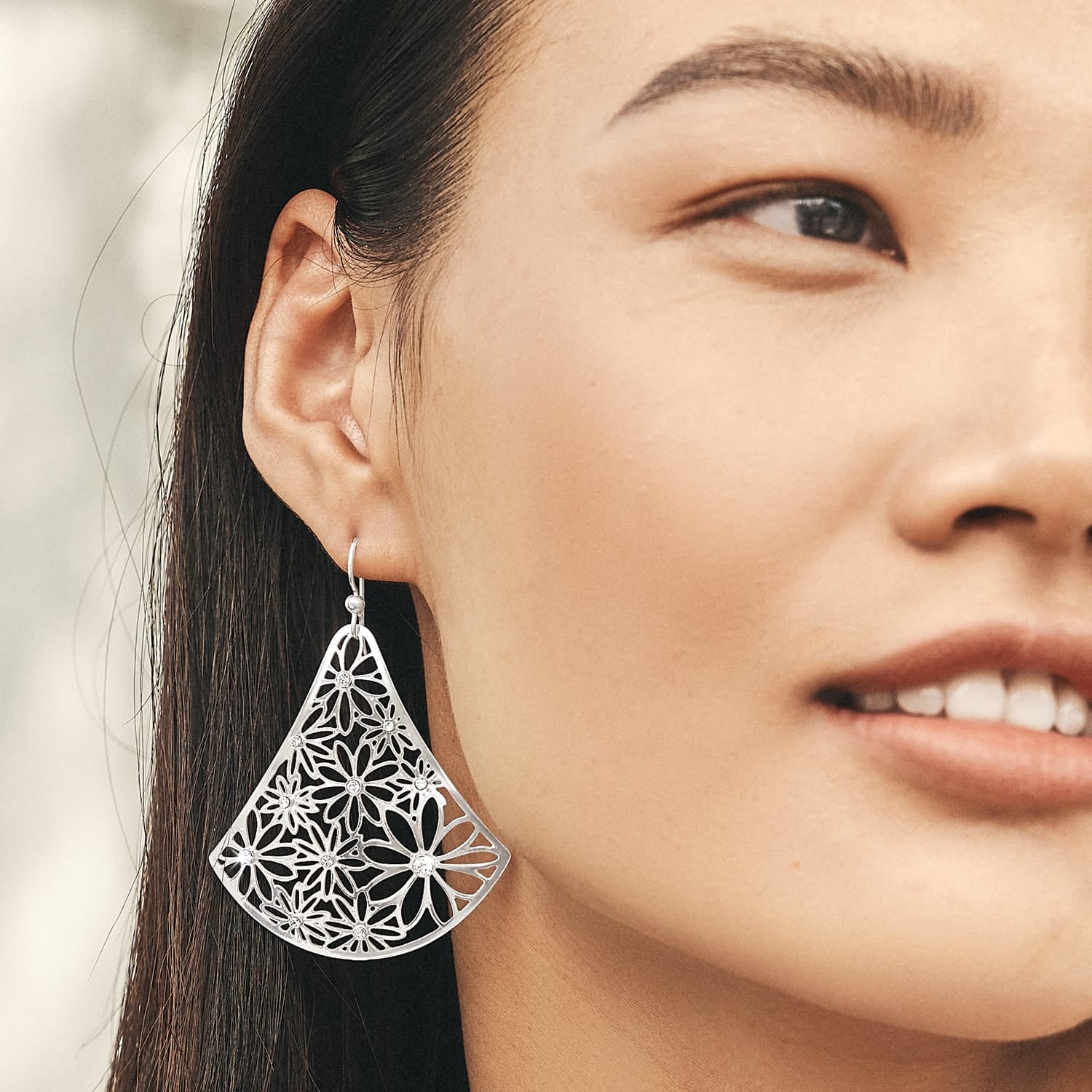 Model wearing a Brighton brushed silver-plated drop earring with fan-shaped floral cutout design and crystal accents