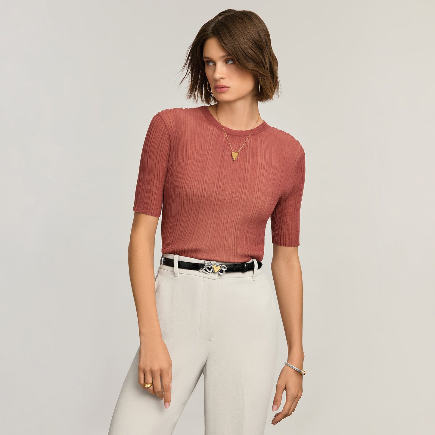Model wearing a Brighton black leather belt with silver-tone scroll and gold-tone heart buckle detail