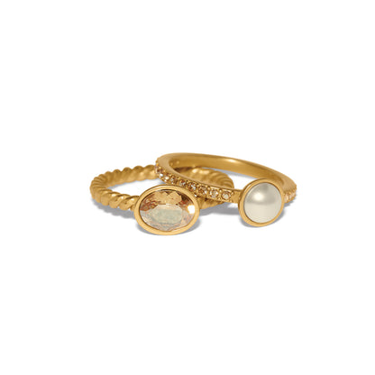 Brighton gold-plated ring set with oval crystal, glass pearl, and twisted and pavé bands on a white background
