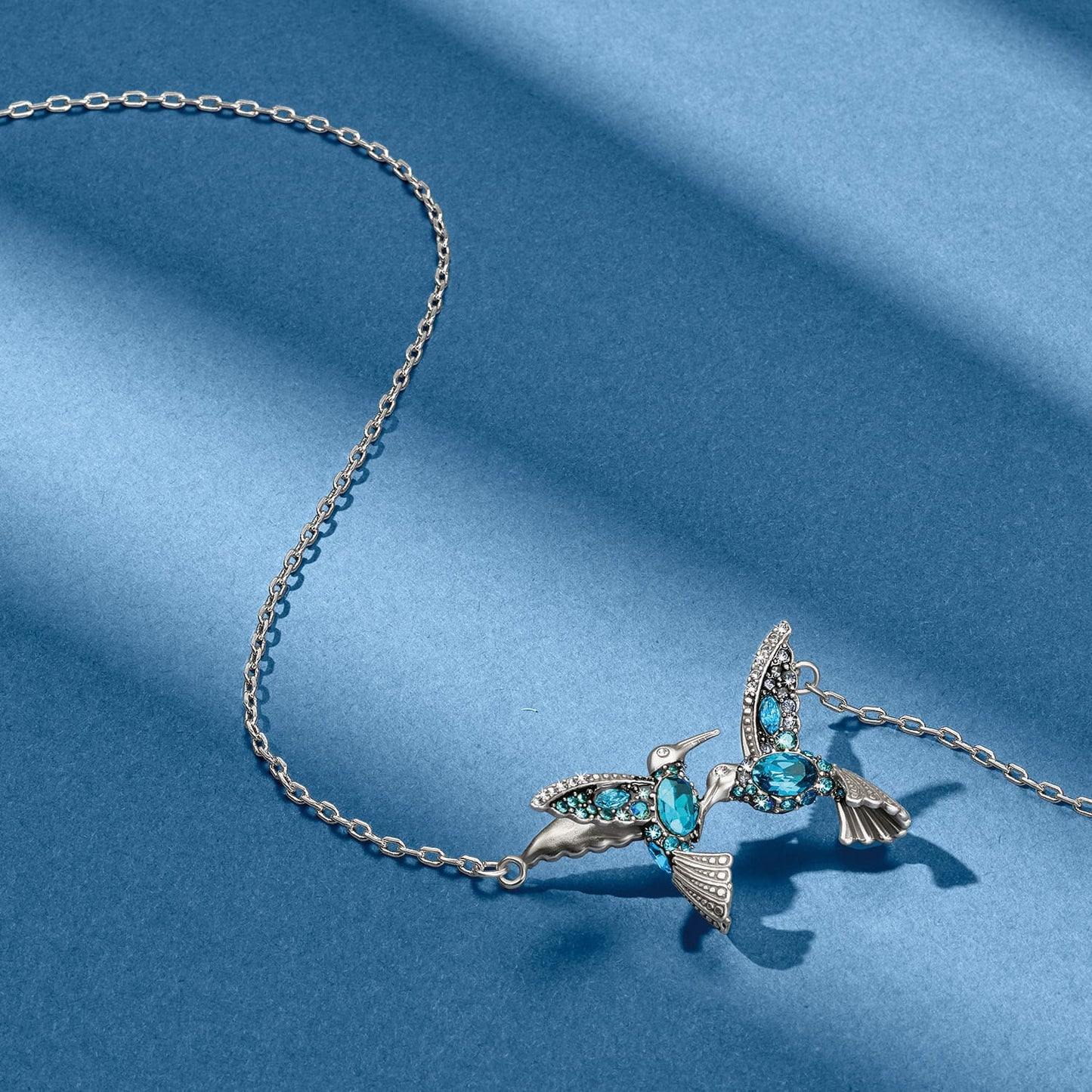 Brighton silver-plated hummingbird pendant necklace with blue and clear crystal accents on a blue background