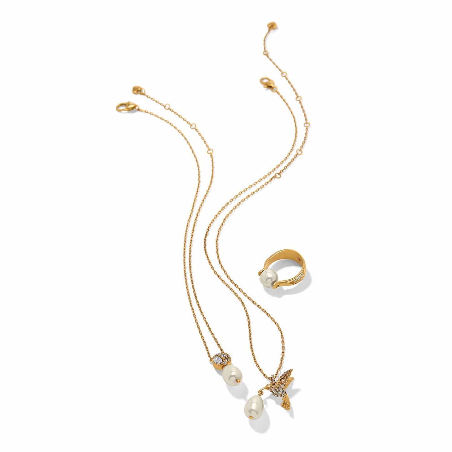 Brighton gold-plated jewelry set styled with pearl pendant necklaces, hummingbird charm, and matching pearl ring on white