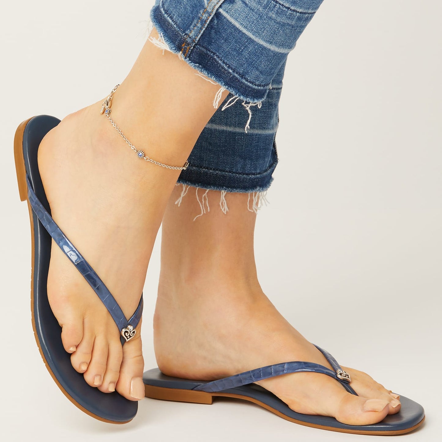 Model wearing Brighton blue thong sandals with silver-plated heart accent at the toe post