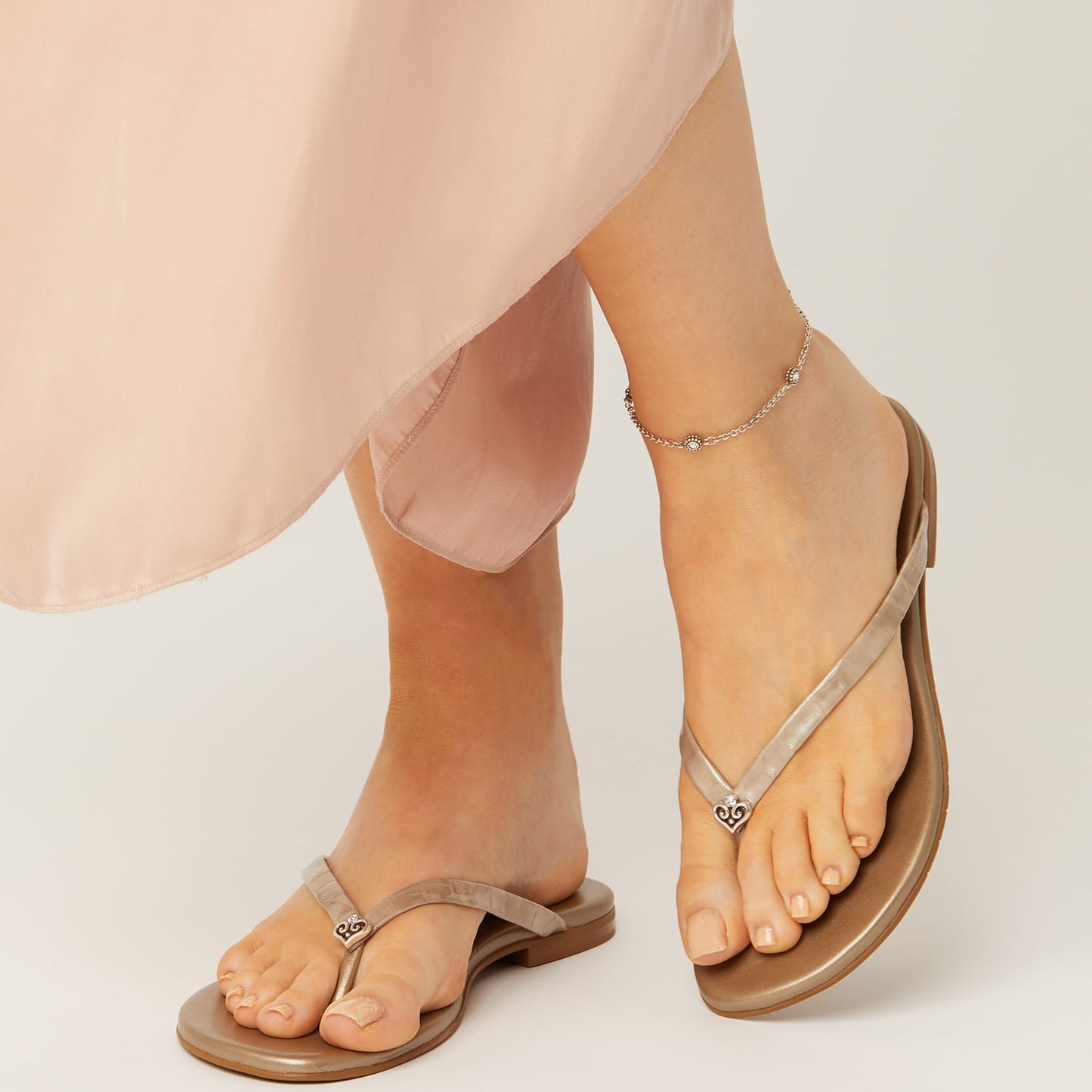 Model wearing Brighton thong sandals with silver-plated heart toe accents, styled with a silver-plated crystal anklet