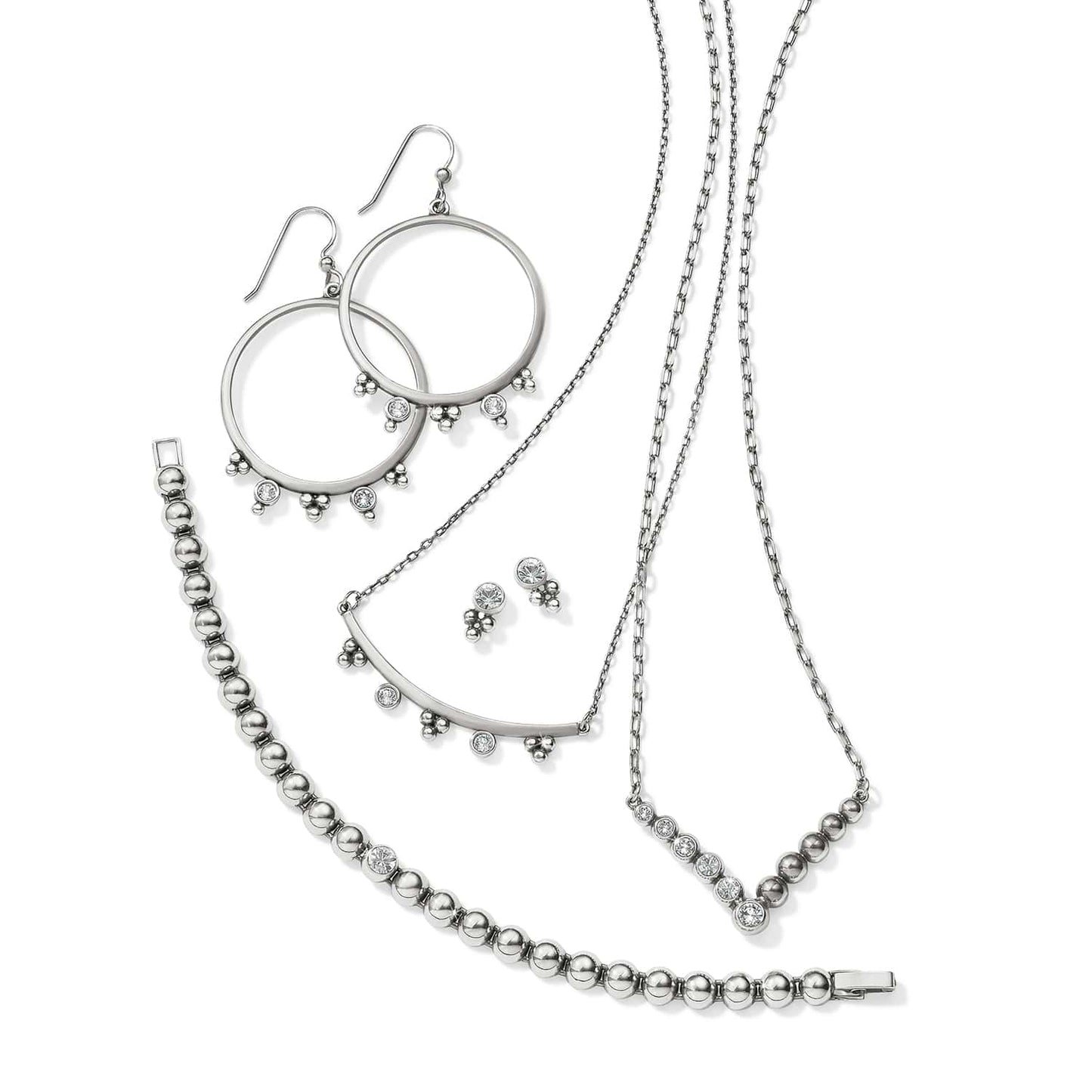 Brighton silver-plated jewelry set styled with hoop earrings, beaded bracelet, and crystal-accented necklaces on white background