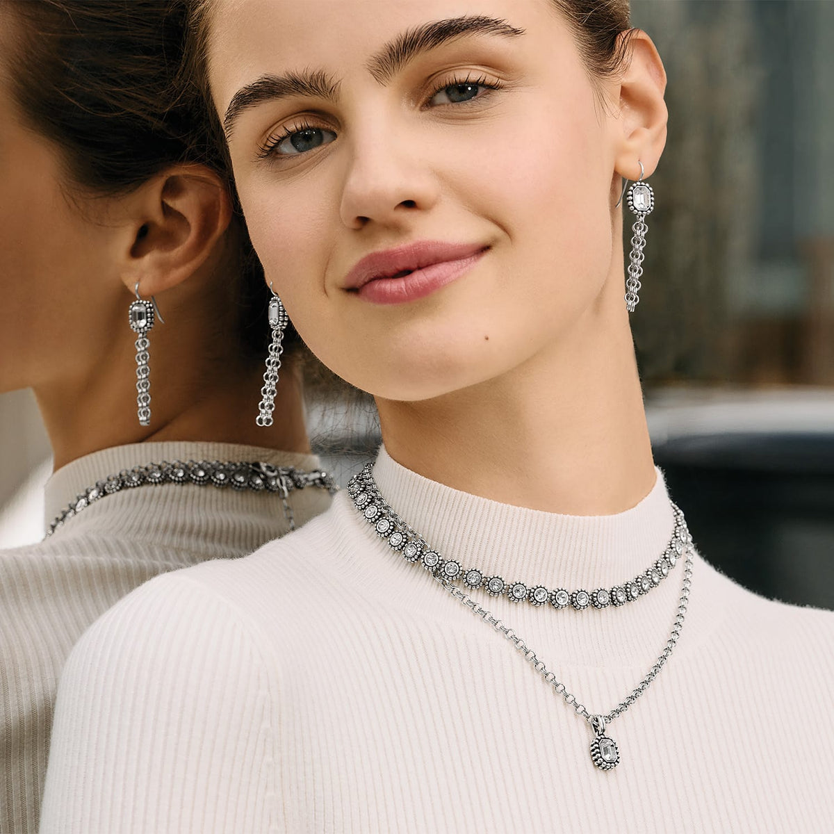 Model wearing Brighton silver-plated drop earrings with crystal accents and coordinating Brighton crystal choker and pendant necklaces
