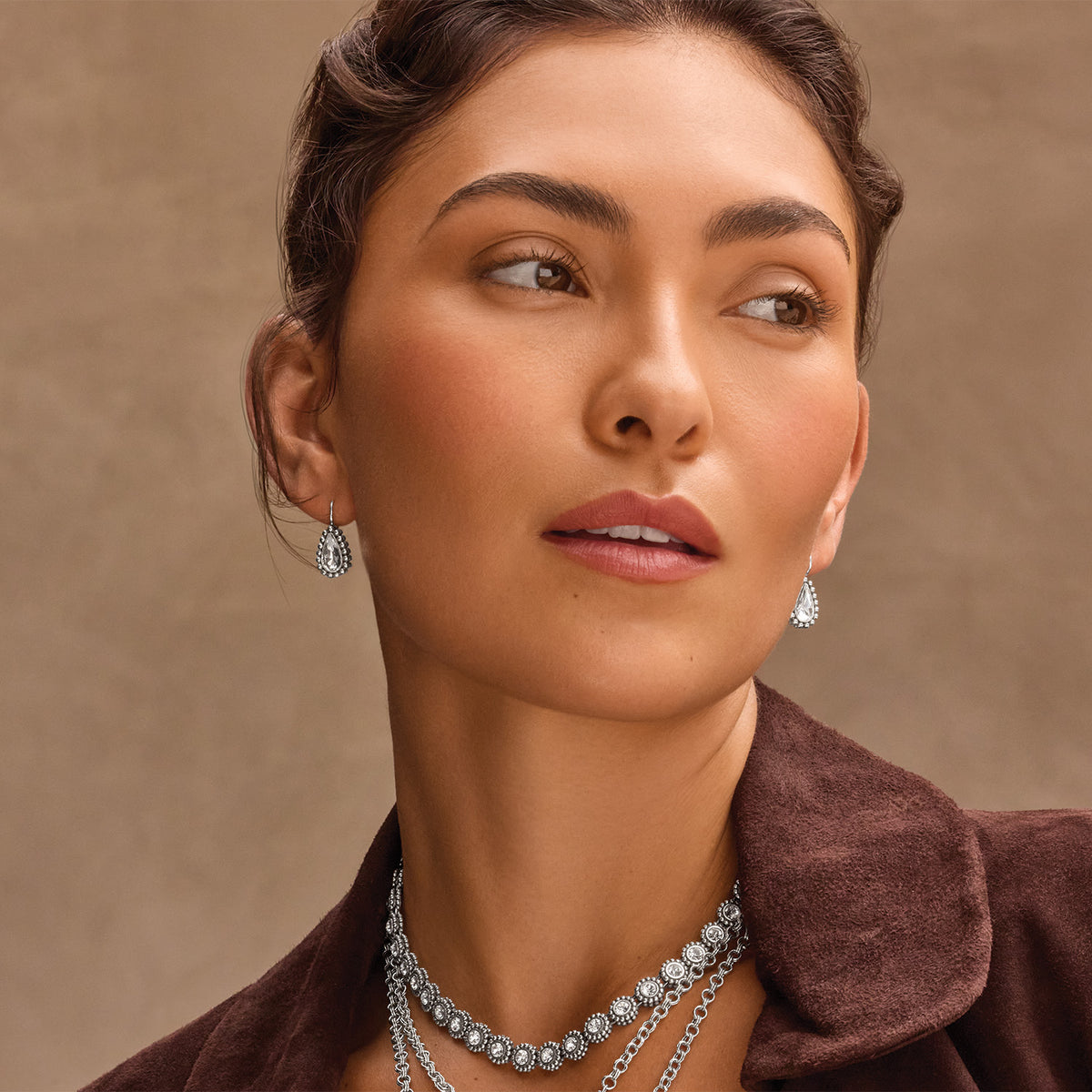 Model wearing Brighton silver-plated teardrop earrings with crystals and coordinating Brighton crystal-accented layered chain necklaces