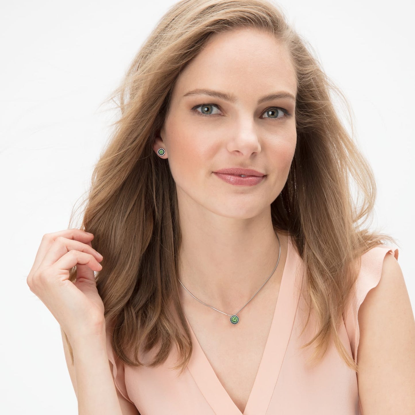 Model wearing a Brighton silver-plated pendant necklace with green crystal paired with matching green crystal stud earrings