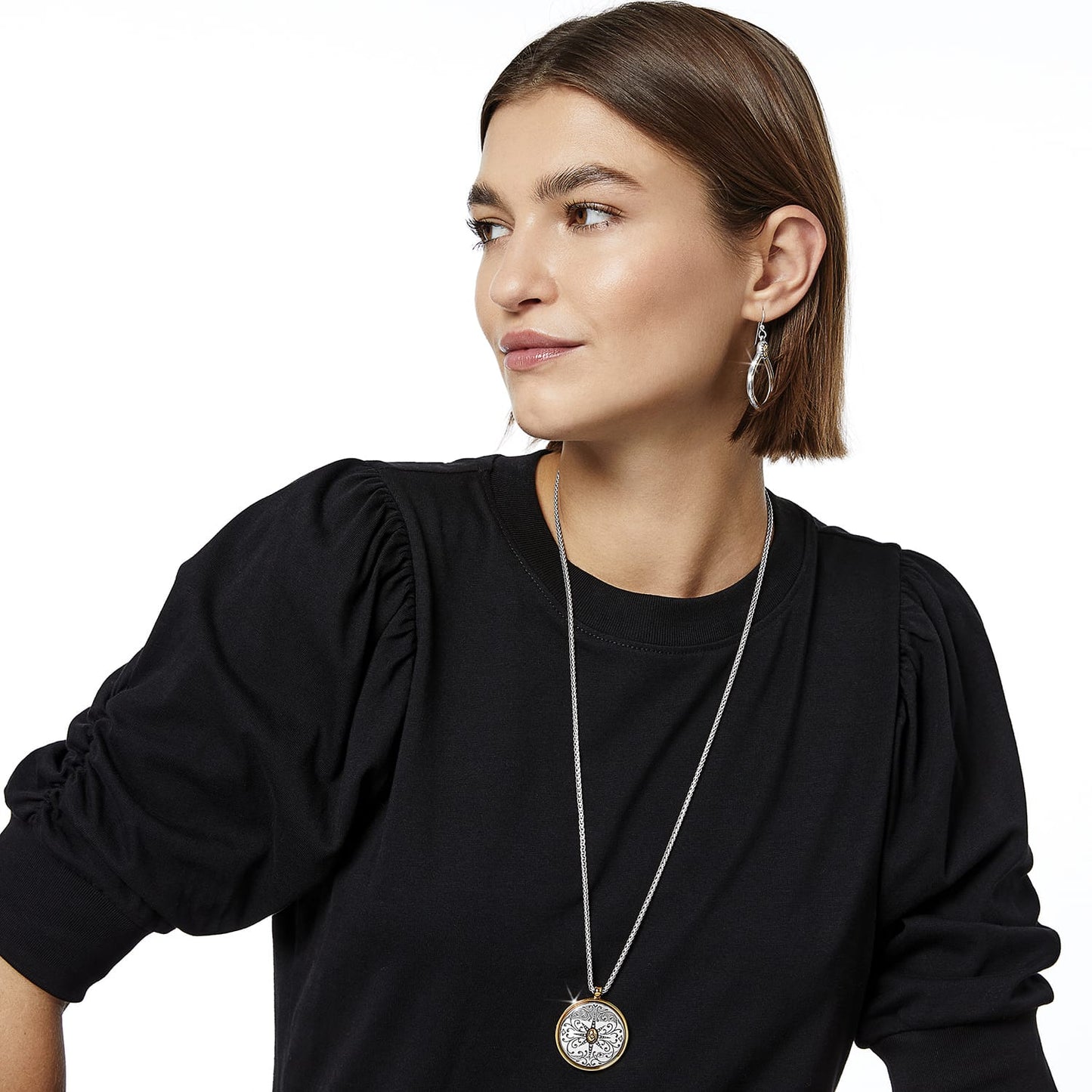 Model wearing a Brighton pendant necklace with two-tone medallion, paired with silver-tone drop earrings