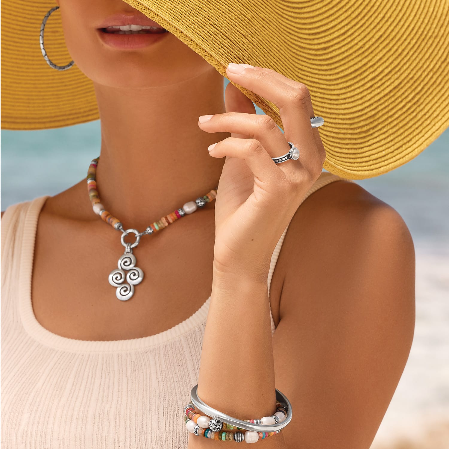 Model wearing a Brighton beaded necklace with silver swirl pendant and coordinating Brighton accessories with mixed gemstones