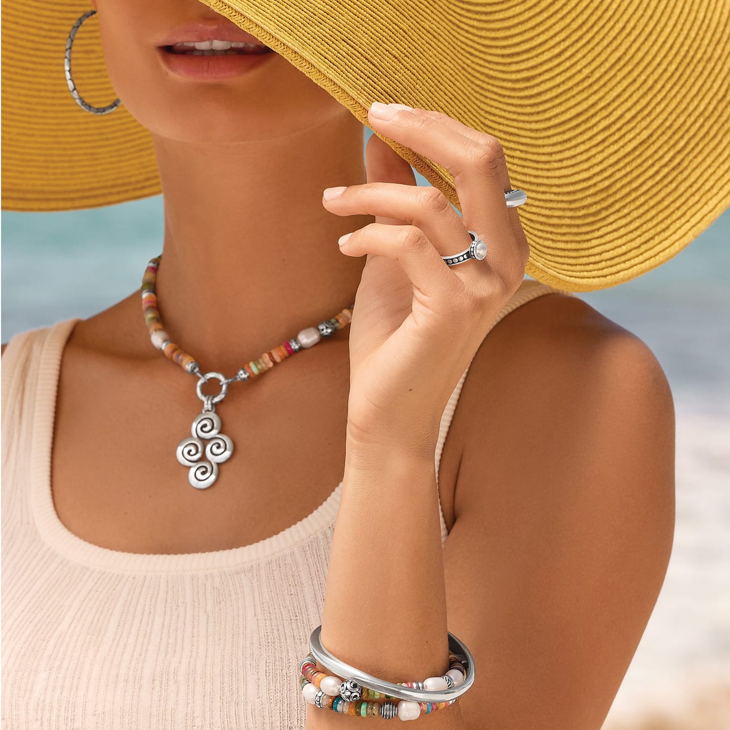 Model wearing a Brighton beaded necklace with silver swirl pendant and coordinating Brighton accessories with mixed gemstones