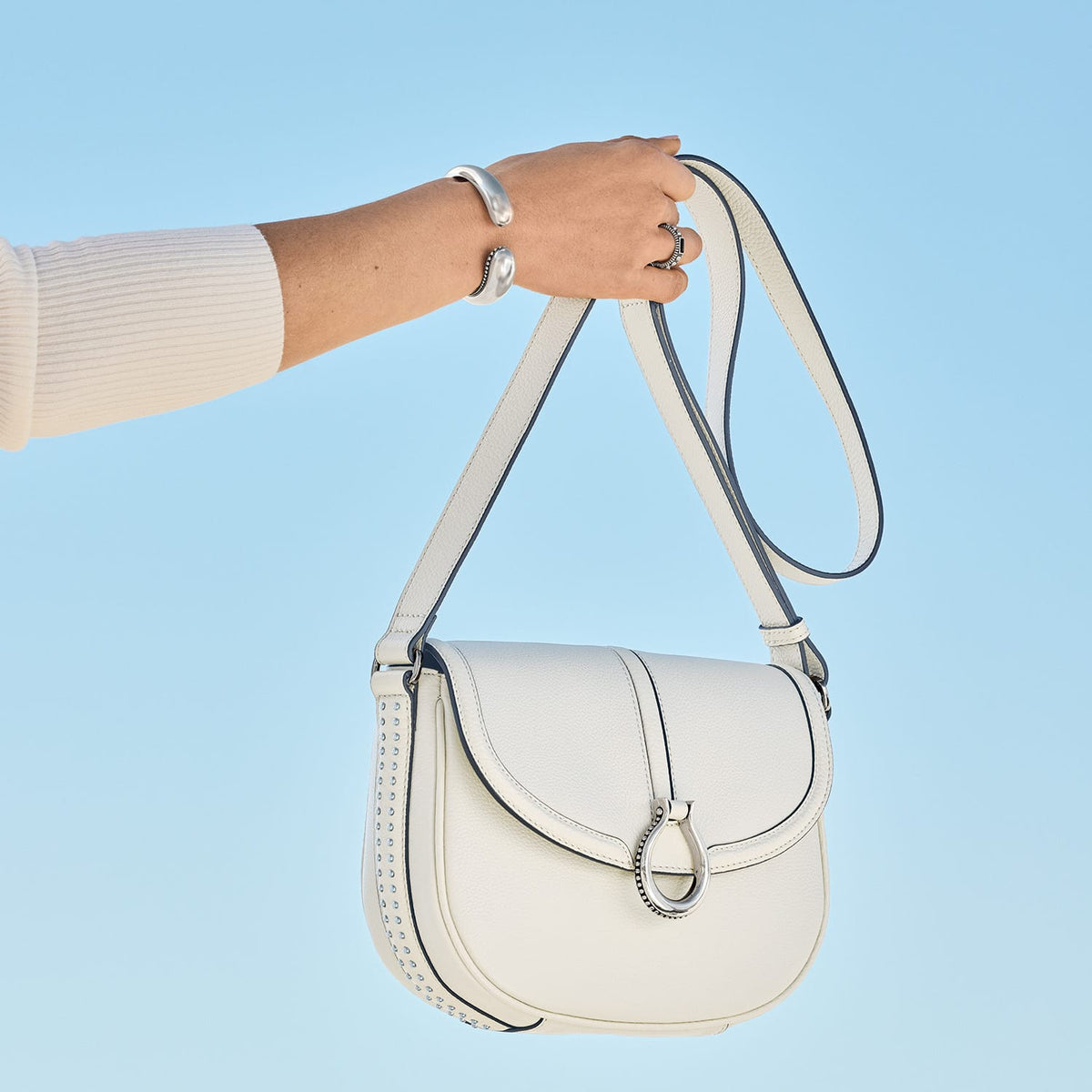 Brighton white leather handbag with silver-tone ring clasp, studded side detail, and adjustable crossbody strap