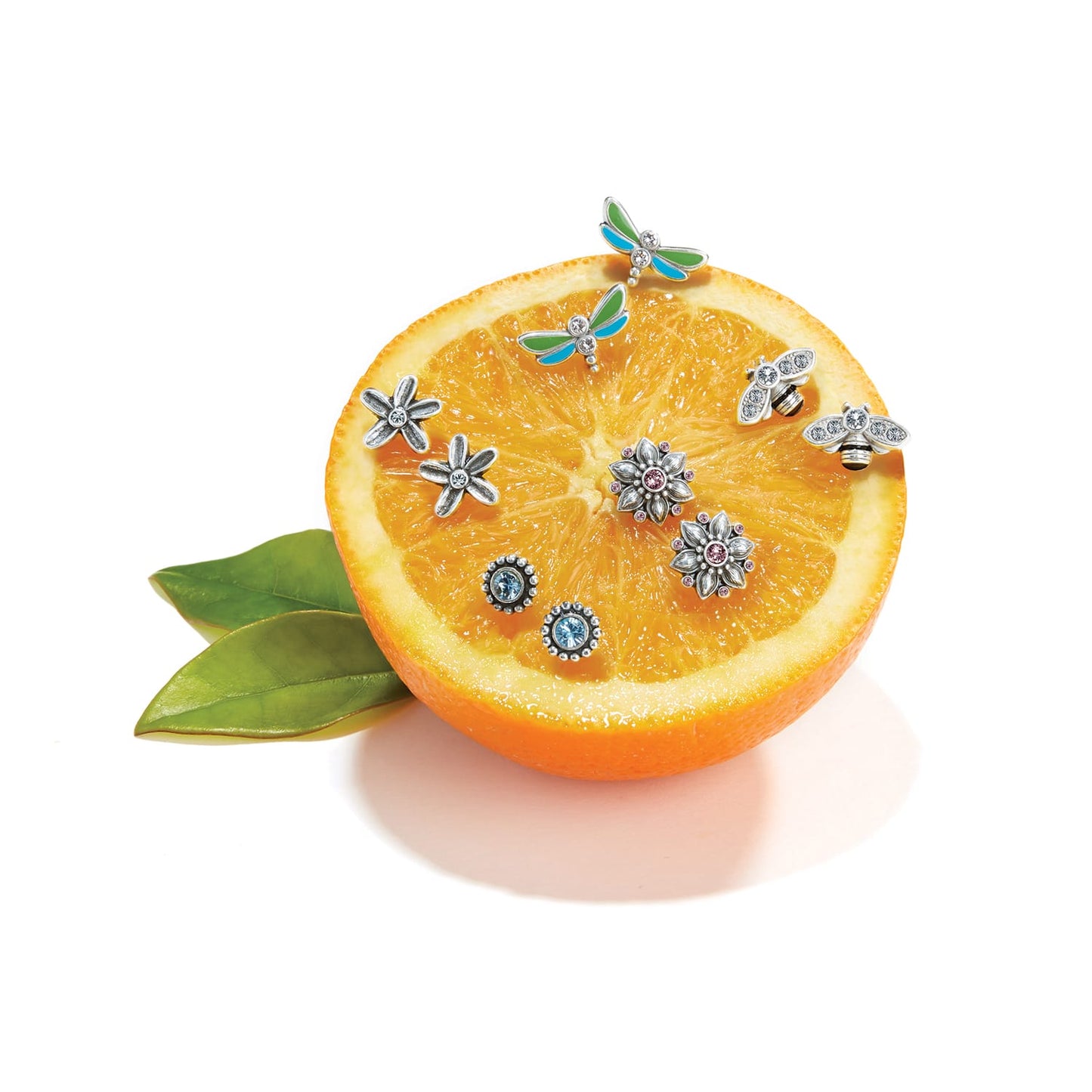 Brighton silver-plated charms styled with an orange slice, featuring enamel dragonflies, crystal bees, and flowers on white