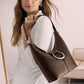 Model with a Brighton brown leather hobo handbag featuring silver-tone studded trim and ring hardware accent
