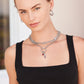 Model wearing layered Brighton silver-plated chain necklaces with heart accents and red crystal charms, paired with hoop earrings