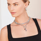 Model wearing layered Brighton silver-plated chain necklaces with heart stations, red crystal charm, and coordinating Brighton accessories