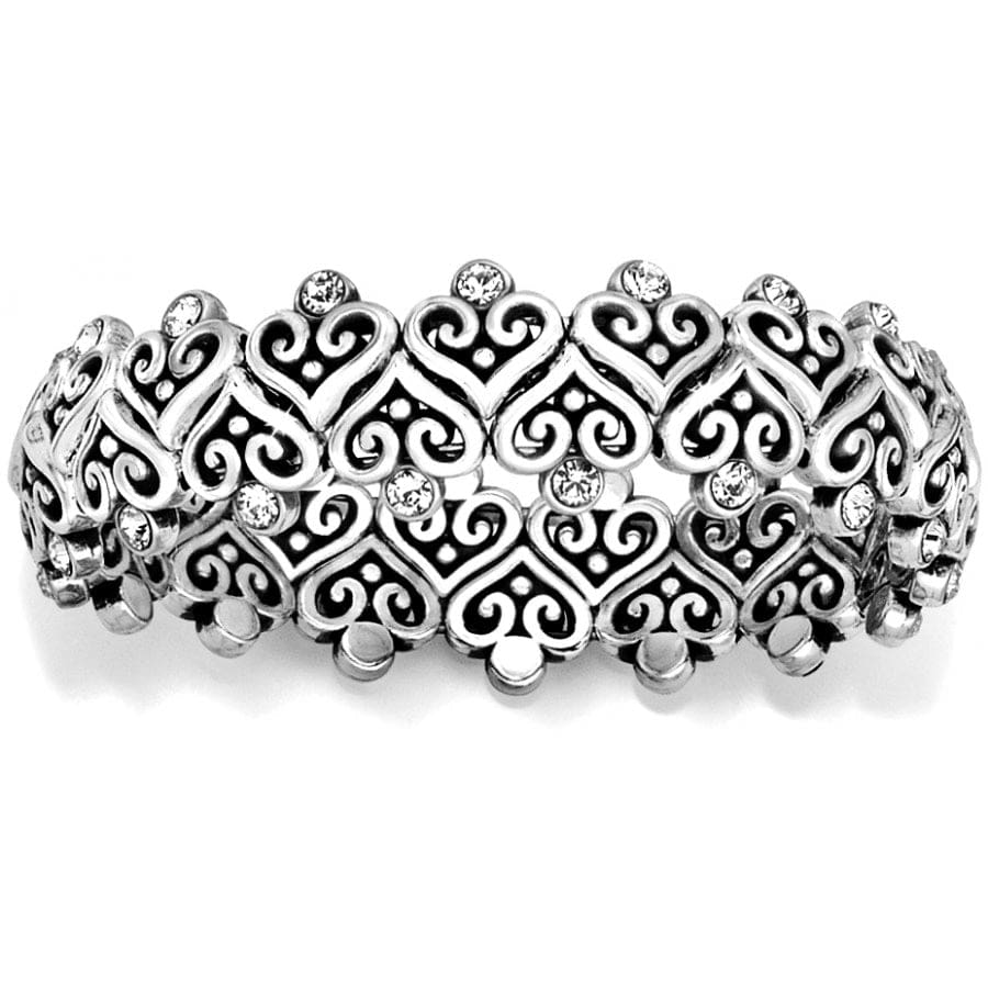 An Alcazar Heart Stretch silver bracelet with intricate scroll patterns and embedded crystals rests against a white background.