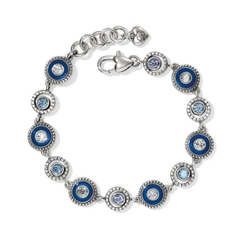 A silver Halo Eclipse Bracelet features alternating blue and white circular settings with embedded gemstones, linked together and secured with a lobster clasp. The background is plain white.