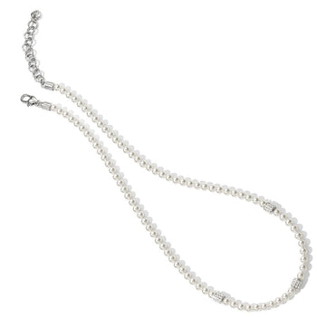 A string of pearls called the Meridian Petite Pearl Station Necklace with two silver clasps and small metal beads is laid out on a plain white background.